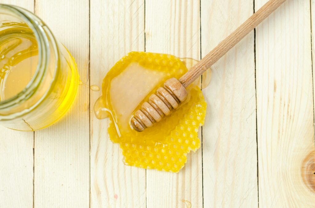 honey comb with honey over it and a wooden honey dipper