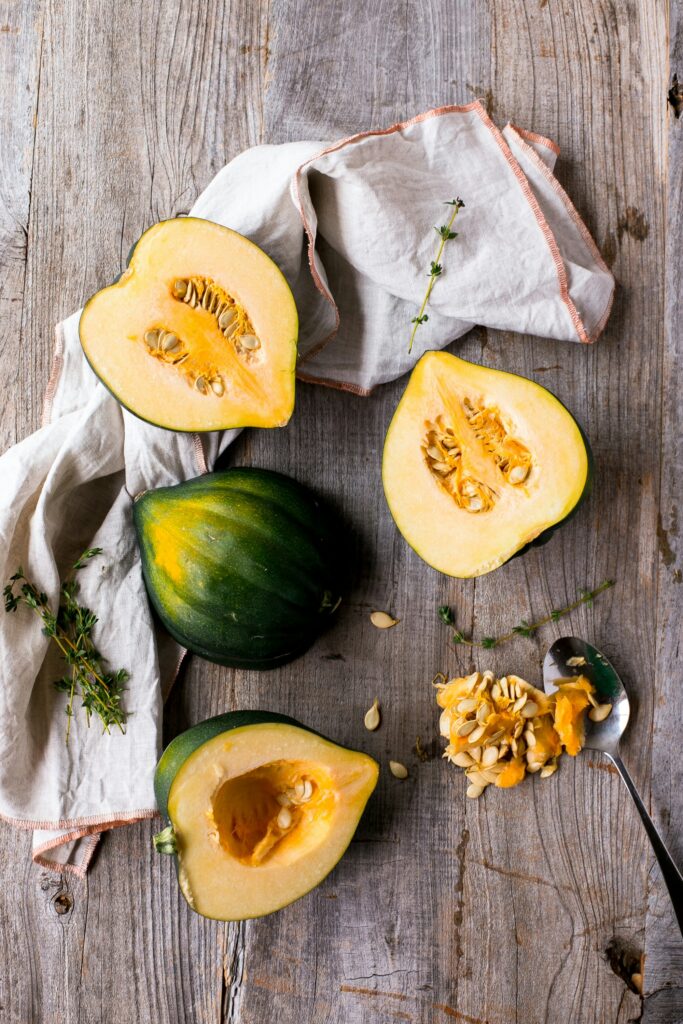 a variety of acorn squash halves strewn over wooden board